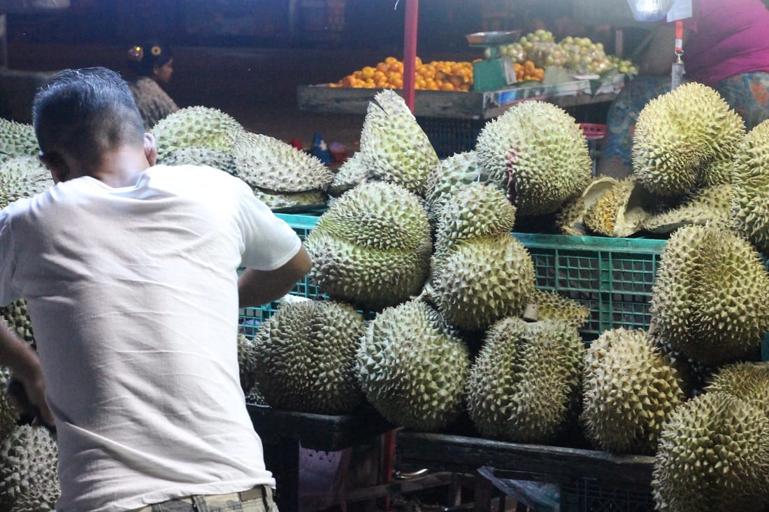 A vendor selling a large spiky fruit